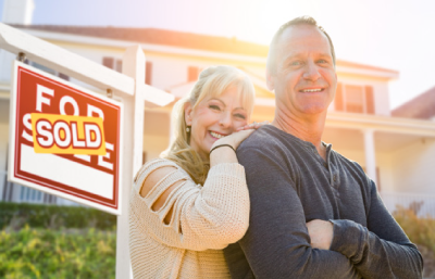 Couple in front of home for sale sign